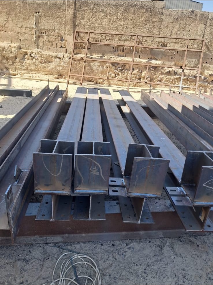 أعمدة وجوائز حديدية مصنّعة بقواعد تثبيت في موقع مشروع E&M — fabricated steel columns and base plates by E&M