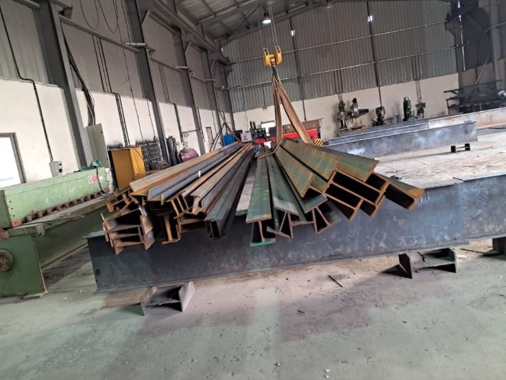 رفع قطاعات حديدية داخل ورشة التصنيع لدى المجموعة الفنية للهندسة والصيانة E&M — steel sections lifted inside the E&M fabrication workshop