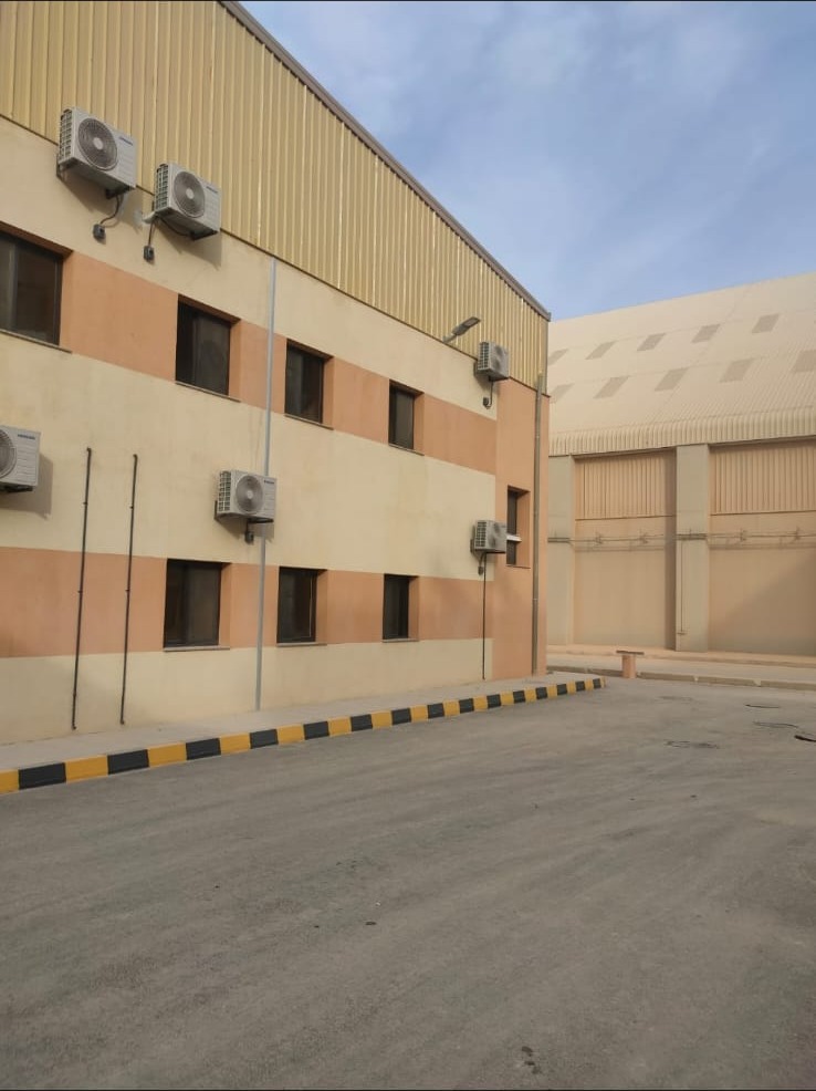 واجهة مبنى صناعي مكتمل مع صالة تخزين من تنفيذ مقاولات E&M في الأردن — completed industrial facility exterior by E&M